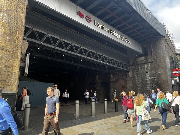 London Bridge Station entrance with commuters walking beneath the rail bridge