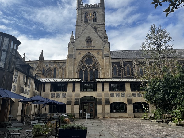 Southwark Cathedral's Gothic tower and courtyard with outdoor café seating