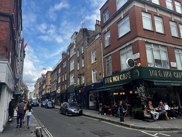 Corner of Berwick Street and D'Arblay Street with café tables outside.